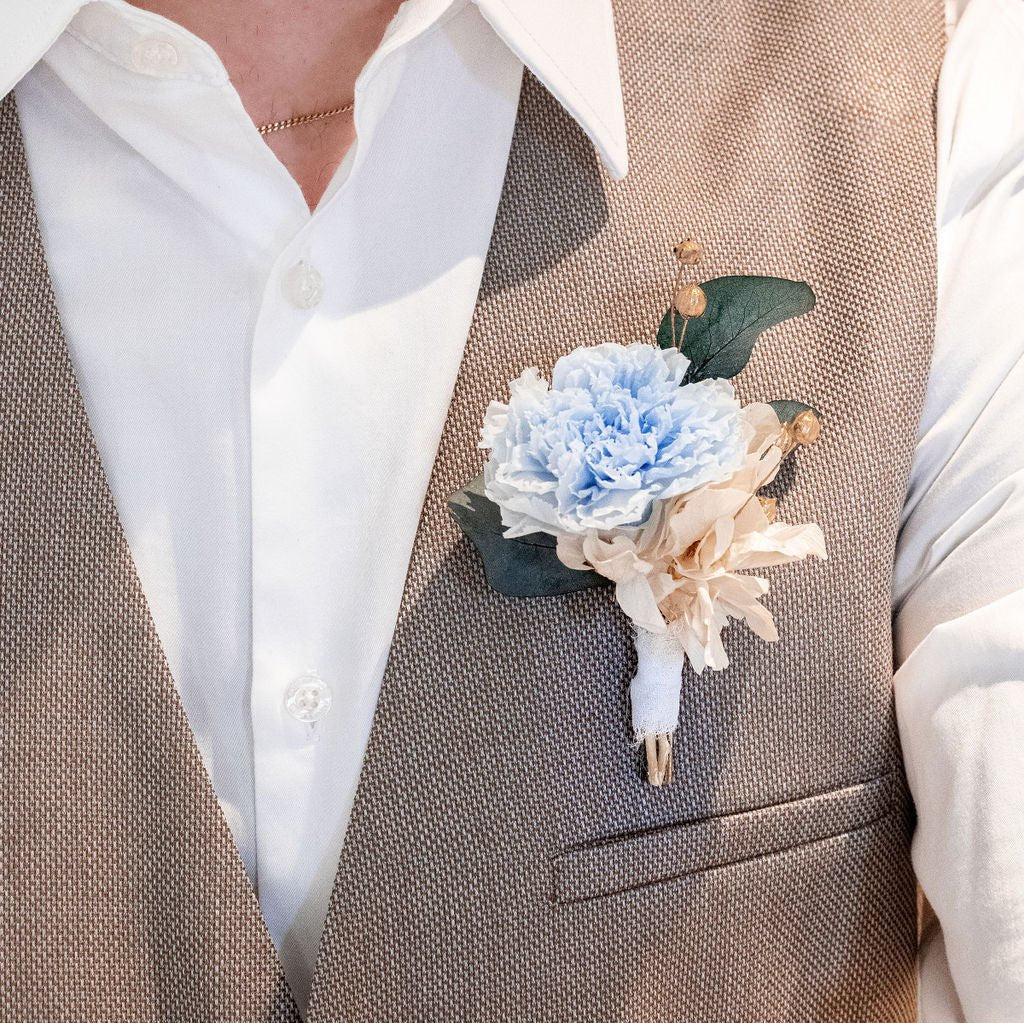 Boutonnière bleue le parfait accessoire pour assortir le marié à la mariée, ajoutant une touche de grâce et de distinction à son ensemble.